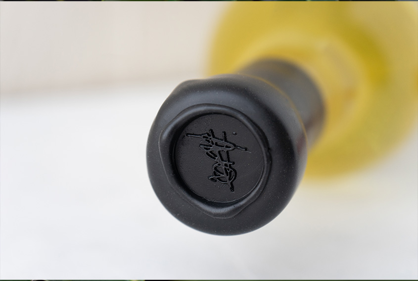Botella vista desde arriba con lacre negro en el cuello de la botella y el logo de un garabato estampado sobre el lacre.