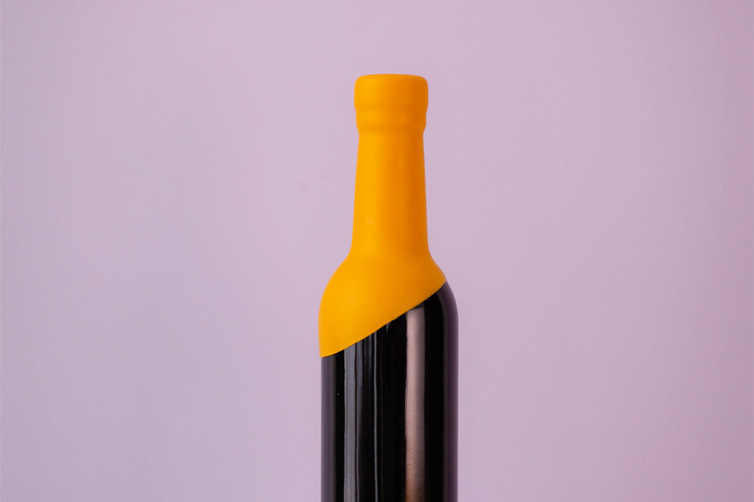 Botella color negro con lacre amarillo en el todo el cuello de la botella dejando en diagonal el lacre, y fondo color lila