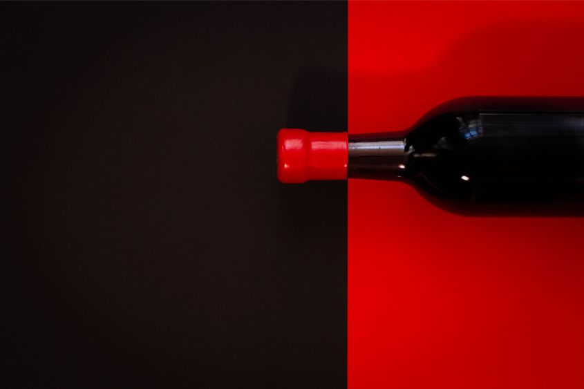 Botella color negro con fondo rojo, y lacre rojo en el cuello de la botella con un fondo negro