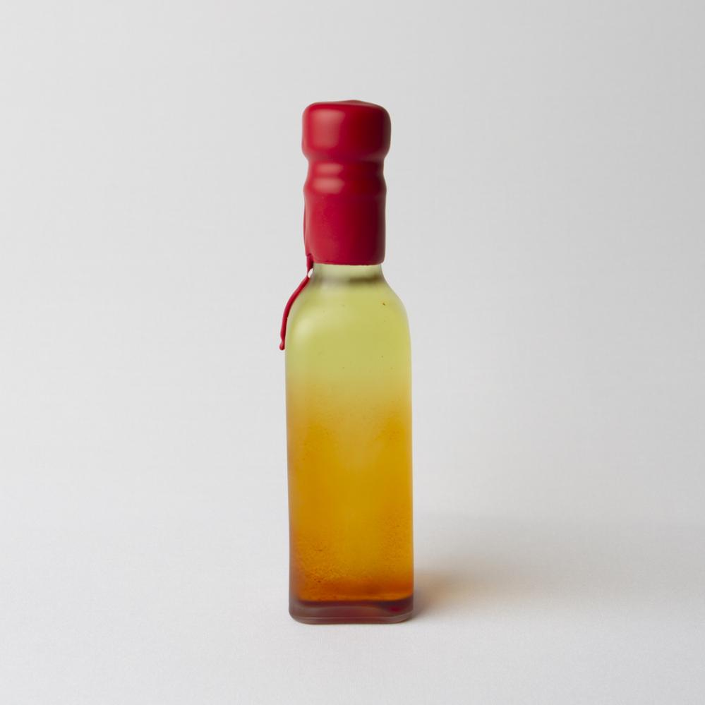 Botella pequeña en tonos naranjas y amarillos, sellada con lacre rojo chorreado
