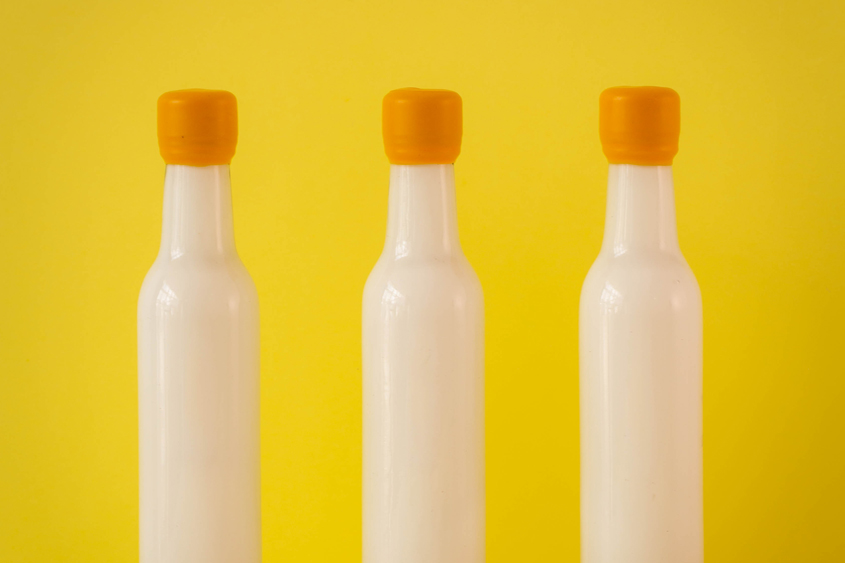 Tres botellas color blanco en fondo color amarillo, y lacre amarillo en el cuello de las botellas