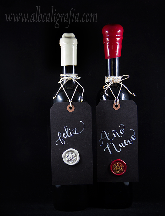 Botellas de vino lacradas con etiquetas colgadas con texto Feliz año nuevo y medallón de lacre sobre la etiqueta