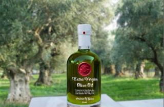 Botella de Aceite de oliva decorada con un medallón de lacre rojo en un paisaje campestre con olivos en el fondo
