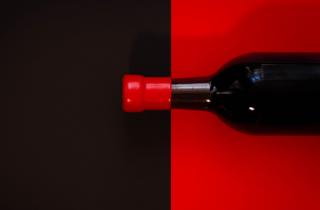 Botella color negro con fondo rojo, y lacre rojo en el cuello de la botella con un fondo negro