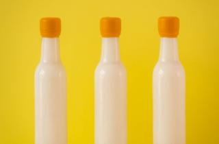 Tres botellas color blanco en fondo color amarillo, y lacre amarillo en el cuello de las botellas